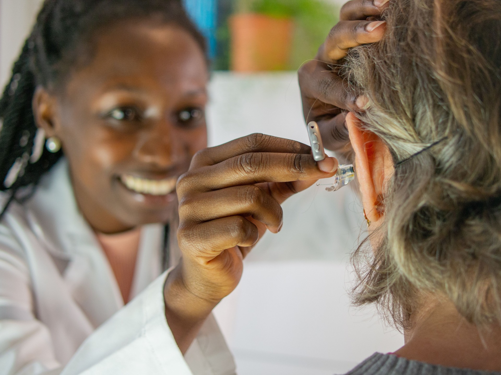 Female Doctor helping senior patient with hearing aid