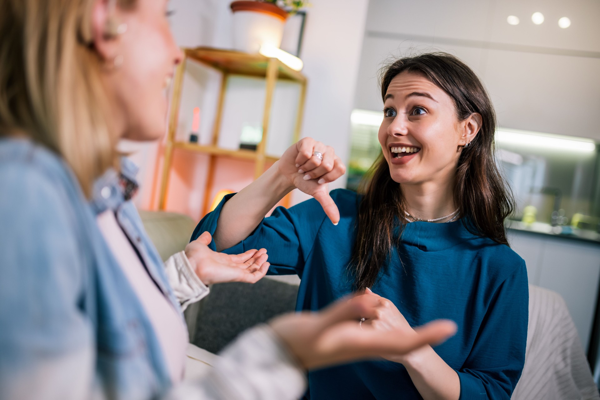 Two Girls Communicating in Sign Language, One Wearing a Hearing Aid