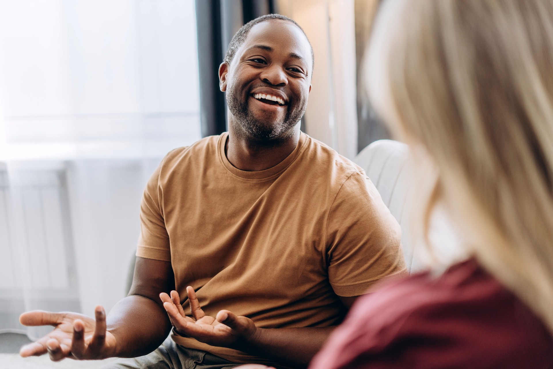 Happy American man with hearing disability making gestures for woman in room